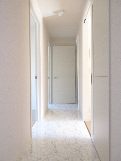 玄関通路：白い天井、白い壁、白い石調の床。